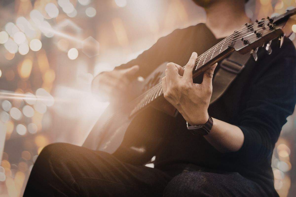A person playing an acoustic guitar under bright, glowing stage lights.